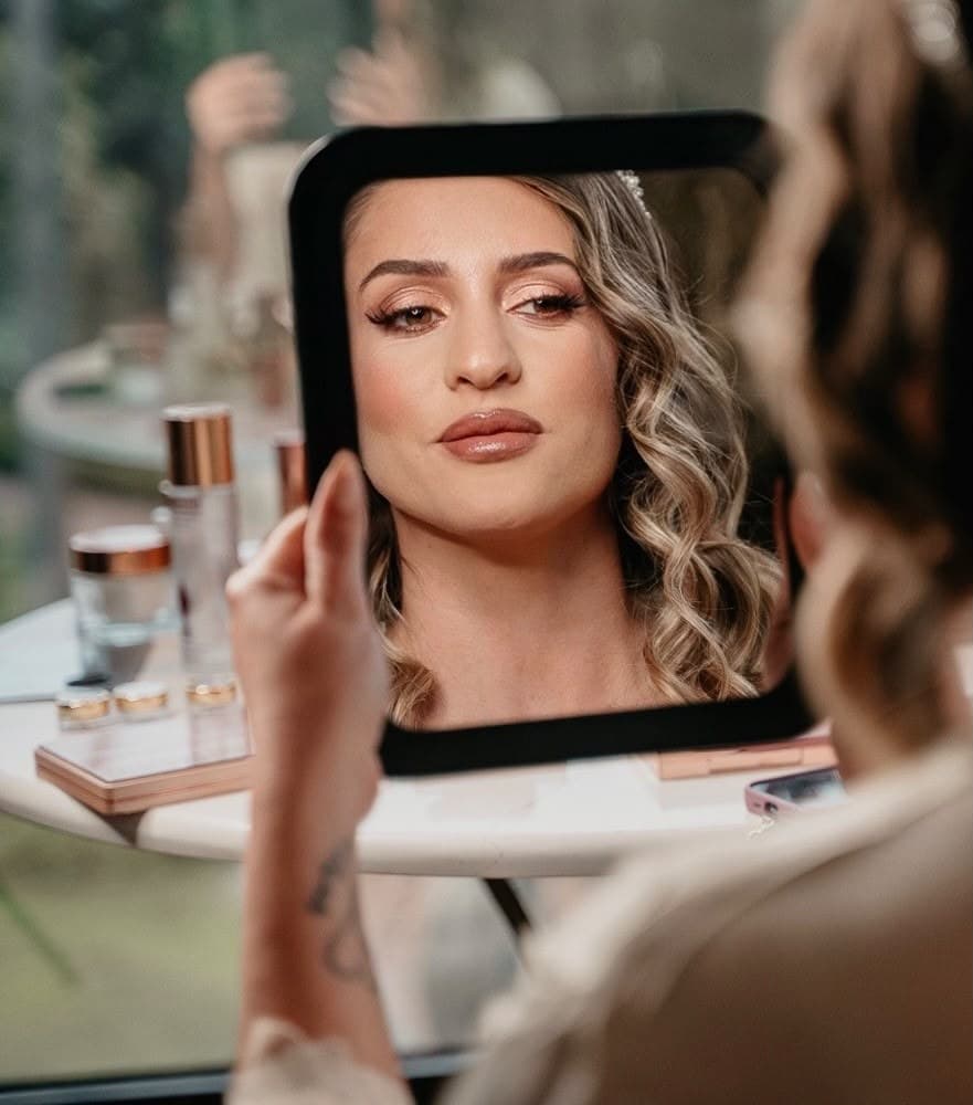 Una invitada mirándose al espejo recién maquillada en una beauty party