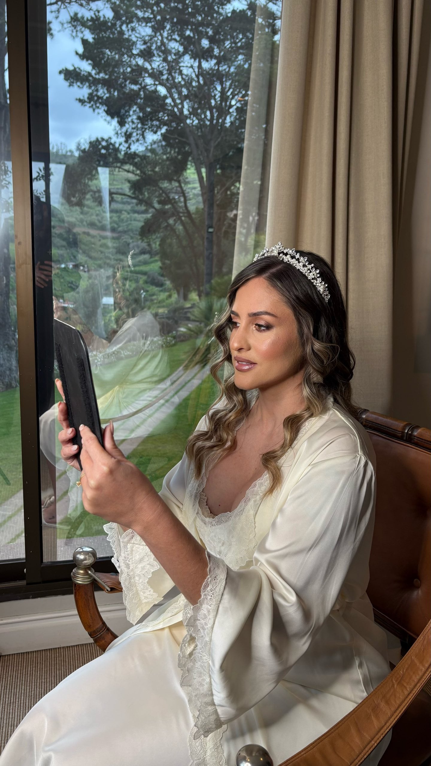 Una novia repasando su look junto a la ventana antes de la ceremonia